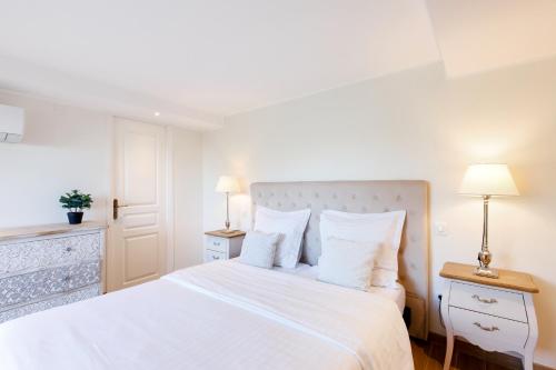 a white bedroom with a large bed and two lamps at Villa d exception avec terrasse, jacuzzi, vue mer, parking, en plein cœur du village de Eze in Éze