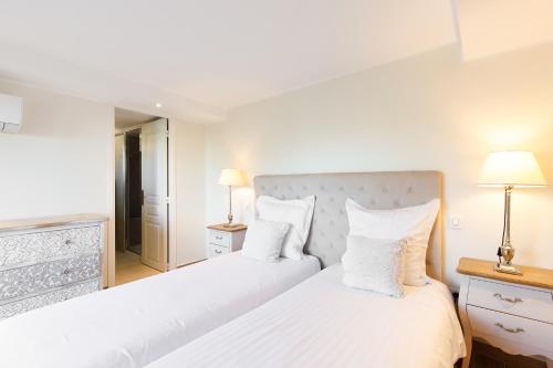 two beds in a white bedroom with two lamps at Villa d exception avec terrasse, jacuzzi, vue mer, parking, en plein cœur du village de Eze in Éze