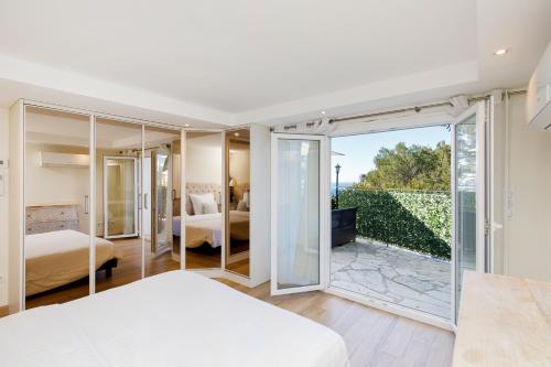 a bedroom with two beds and a balcony at Villa d exception avec terrasse, jacuzzi, vue mer, parking, en plein cœur du village de Eze in Èze