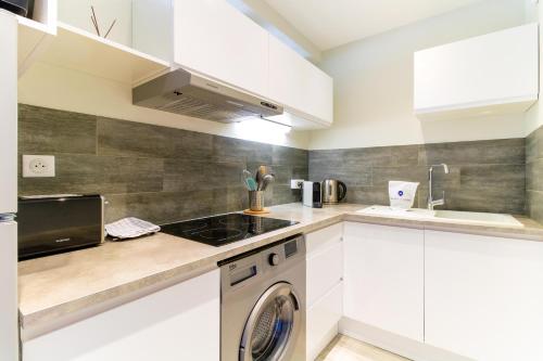 cocina con armarios blancos y lavavajillas en SELECT'SO HOME - Studio au cœur du Lavandou-Services hôteliers-AREV, en Le Lavandou