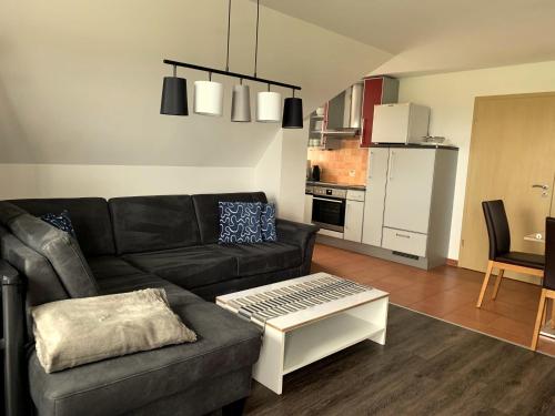 a living room with a black couch and a kitchen at Ferienhaus Sunset in Gräfensteinberg