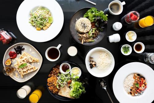 a table topped with plates of food and drinks at Away Chiang Mai Thapae Resort A Vegan Retreat in Chiang Mai