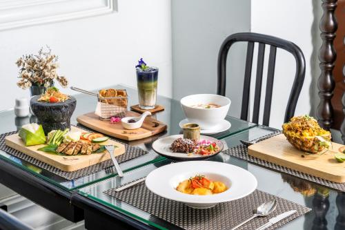 a glass table with plates of food on it at Away Chiang Mai Thapae Resort A Vegan Retreat in Chiang Mai