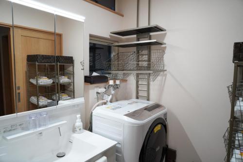 a laundry room with a washing machine and a mirror at Hakodate MOTOMACHI guesthouse in Hakodate