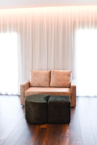 a couch and an ottoman in a living room at Olivia's Hill Resort in Durrës
