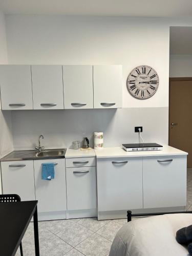 a kitchen with white cabinets and a clock on the wall at Affittacamere Viali centro Chivasso in Chivasso