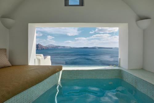 a bedroom with a swimming pool with a view of the ocean at Allure Breeze Suites in Oia