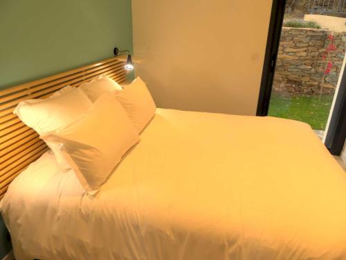 - un lit avec des draps et des oreillers blancs ainsi qu'une fenêtre dans l'établissement Les Terrasses d'Erbalunga, à Erbalunga