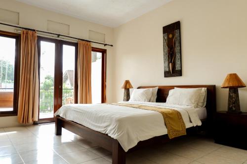 a bedroom with a large bed and a large window at Puri Panca Jaya Hotel in Seminyak