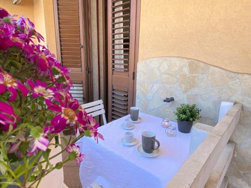 une table blanche avec des tasses, des soucoupes et des fleurs dans l'établissement Maison Soleil Guest House Gallipoli, à Gallipoli