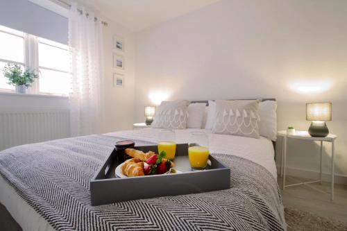 a tray of food on a bed with two glasses of orange juice at Apartments in the heart of Penzance in Penzance