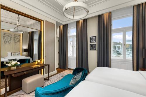 a bedroom with a bed and a desk and a mirror at Matild Palace, a Luxury Collection Hotel in Budapest