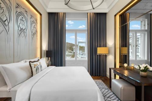 a bedroom with a large white bed and a desk at Matild Palace, a Luxury Collection Hotel in Budapest