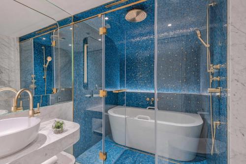 a bathroom with a tub and a shower with blue tiles at Matild Palace, a Luxury Collection Hotel in Budapest