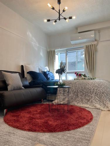 a living room with a black couch and a red rug at BEST LOCATED SHINJUKU CENTRAL Full-Furnished APARTMENT 3minWalk to Station1 in Tokyo