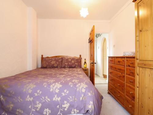 ein Schlafzimmer mit einem Bett und einer Holzkommode in der Unterkunft 21 Crossways in Clacton-on-Sea
