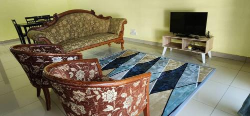 uma sala de estar com uma mesa com cadeiras e uma televisão em Bertam Homestay Kepala Batas em Kepala Batas