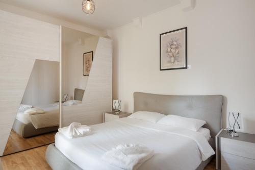 biała sypialnia z 2 łóżkami i lustrem w obiekcie Suite Foscolo, comfort con box auto a Trieste w Trieście