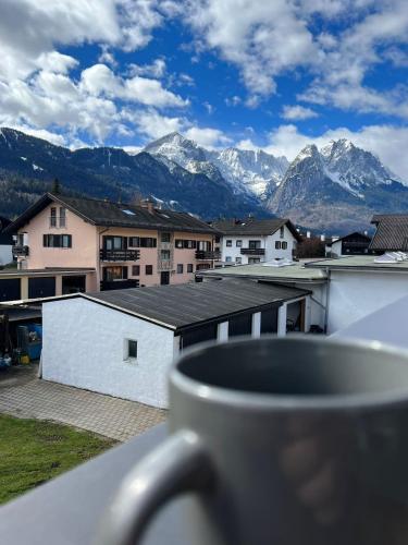 a cup of coffee sitting on a balcony with mountains at Ferienhaus Butterfly 2 in Garmisch-Partenkirchen