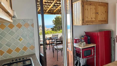 a kitchen with a red refrigerator and a balcony with a table at Villa la Milanina in Lipari