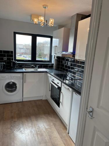 a kitchen with a sink and a washing machine at River view Apartment in Glasgow
