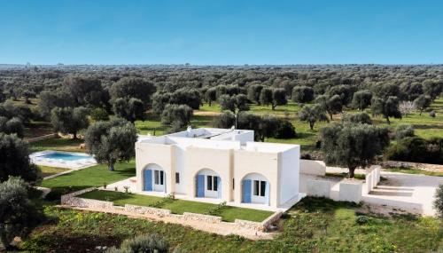 - une vue aérienne sur une maison blanche avec une piscine dans l'établissement Dimora La Scaledda, à Serranova