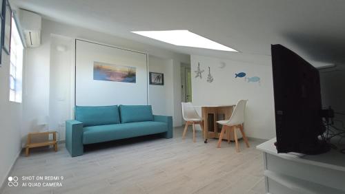 ein Wohnzimmer mit einem blauen Sofa und einem Tisch in der Unterkunft Monolocale mansarda a Porto Santo Stefano Argentario in Porto Santo Stefano