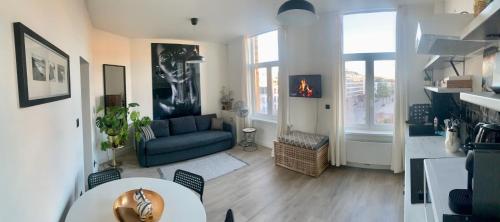 a living room with a blue couch and a table at SLEEP INN - Black and White modern flat with cityview in Antwerp