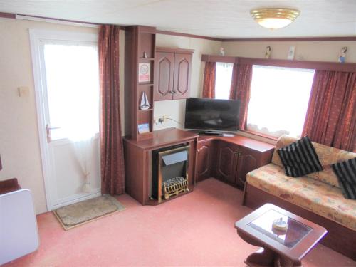 a living room with a couch and a television at Seaways : The Westmorland SW:- 6 Berth, Enclosed Veranda in Lincolnshire