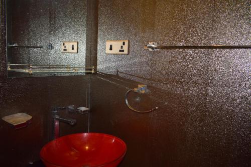 a bathroom with a red toilet in a stall at Alffa Guest Inn in Trincomalee