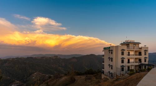 a building on top of a hill with a sunset at Viable Inn by Vista Stays in Mukteswar