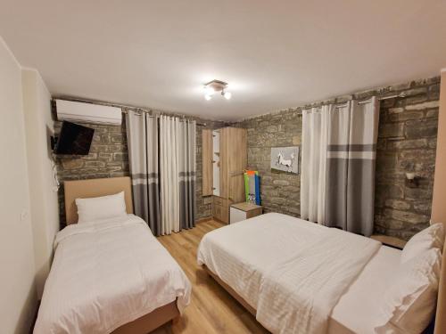 a bedroom with two beds and a television in it at The Stone House in Përmet