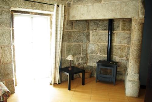 a room with a stone wall with a stove at As Casiñas in Ribadavia