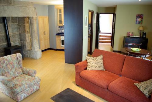 a living room with a red couch and a chair at As Casiñas in Ribadavia