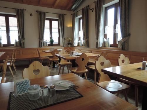 a restaurant with wooden tables and chairs and windows at Gasthof Stocker in Landsham