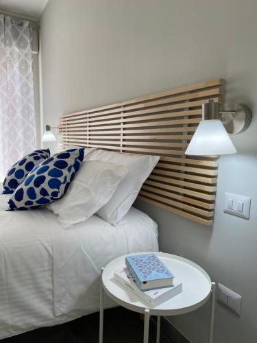 a bed with pillows and a table with a book on it at ViaRiva Rooms in Cagliari