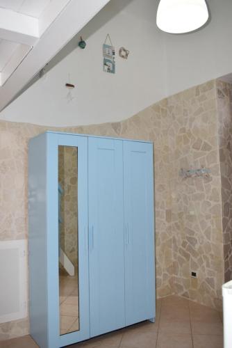 un meuble bleu dans une pièce avec un mur en pierre dans l'établissement Chicca marina, à Torre Canne