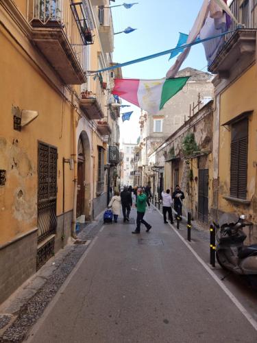 un grupo de personas caminando por una calle en un callejón en San Ciro's apartment, en Portici