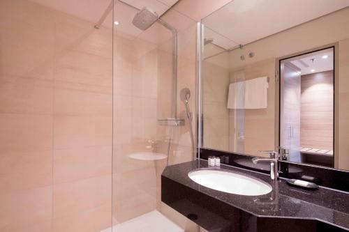 a bathroom with a sink and a glass shower at Sheraton Duesseldorf Airport Hotel in Düsseldorf