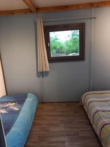 une chambre avec deux lits et une fenêtre dans l'établissement Chalet 5 personnes vallée du lot, à Laburgade