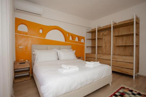 een slaapkamer met een bed met witte lakens en planken bij Erik's Place in Shkodër
