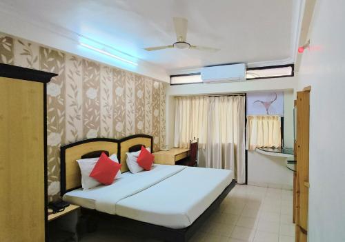 a bedroom with a white bed with red pillows at Hotel Kanak Sagar in Ajmer