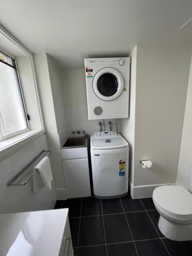 y baño pequeño con aseo y lavadora. en Cascade Gardens Apartments, en Gold Coast