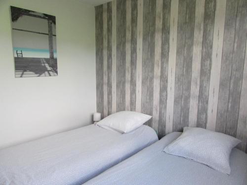 2 camas en un dormitorio con una pared a rayas en Gîte de la Grenouille, en La Cambe
