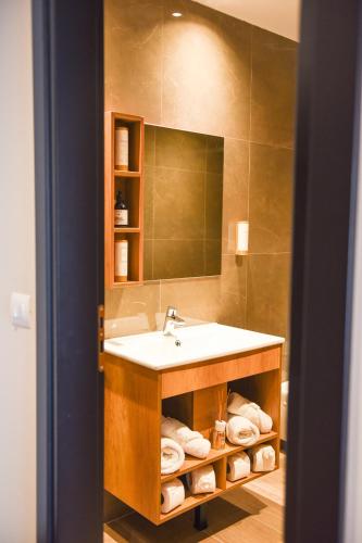 a bathroom with a sink and a mirror and towels at Olivia's Hill Resort in Durrës