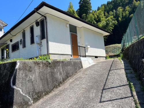 a small house on a road next to a fence at ゆふの音 in Yufuin