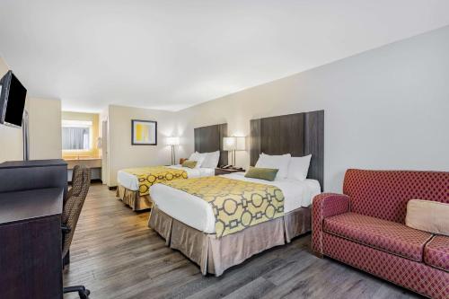 a hotel room with two beds and a couch at Baymont by Wyndham Midway Tallahassee in Midway