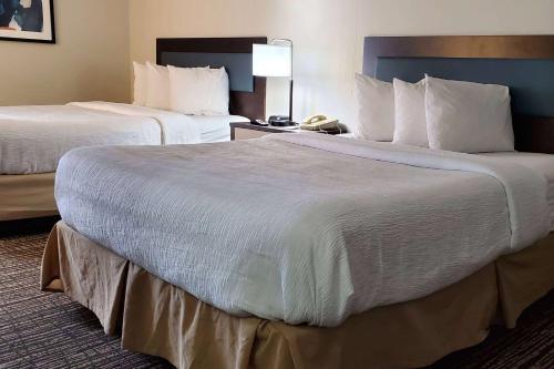 a hotel room with two beds with white sheets at Wingate by Wyndham Canton-Hall of Fame in Canton