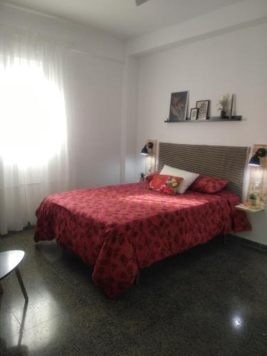 a bedroom with a bed with a red blanket and a window at Sevilla Macarena apartamento 3 dormitorios in Seville