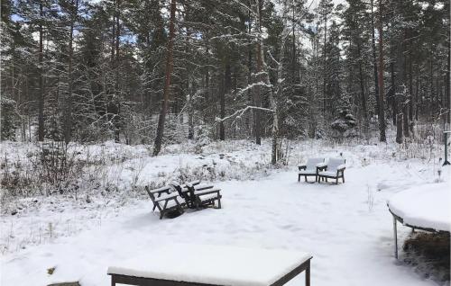 three picnic benches in the snow in a forest at Gorgeous Home In Herräng With Kitchen in Herräng
